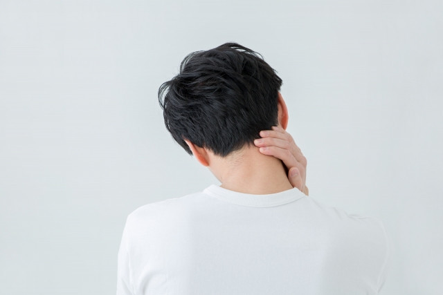 首こりのため、首のこりを触る男性写真